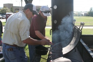Student check on meat in a BBQ smoker.