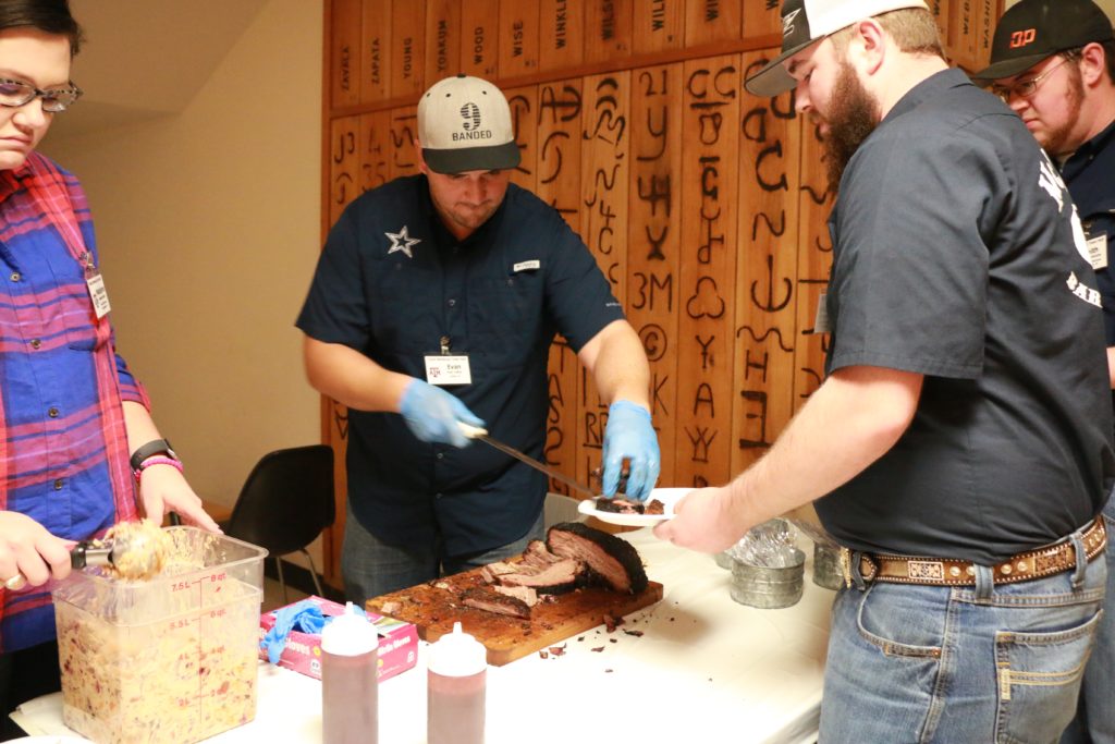 Evan LeRoy serving beef chuck roll and pork brisket to participants