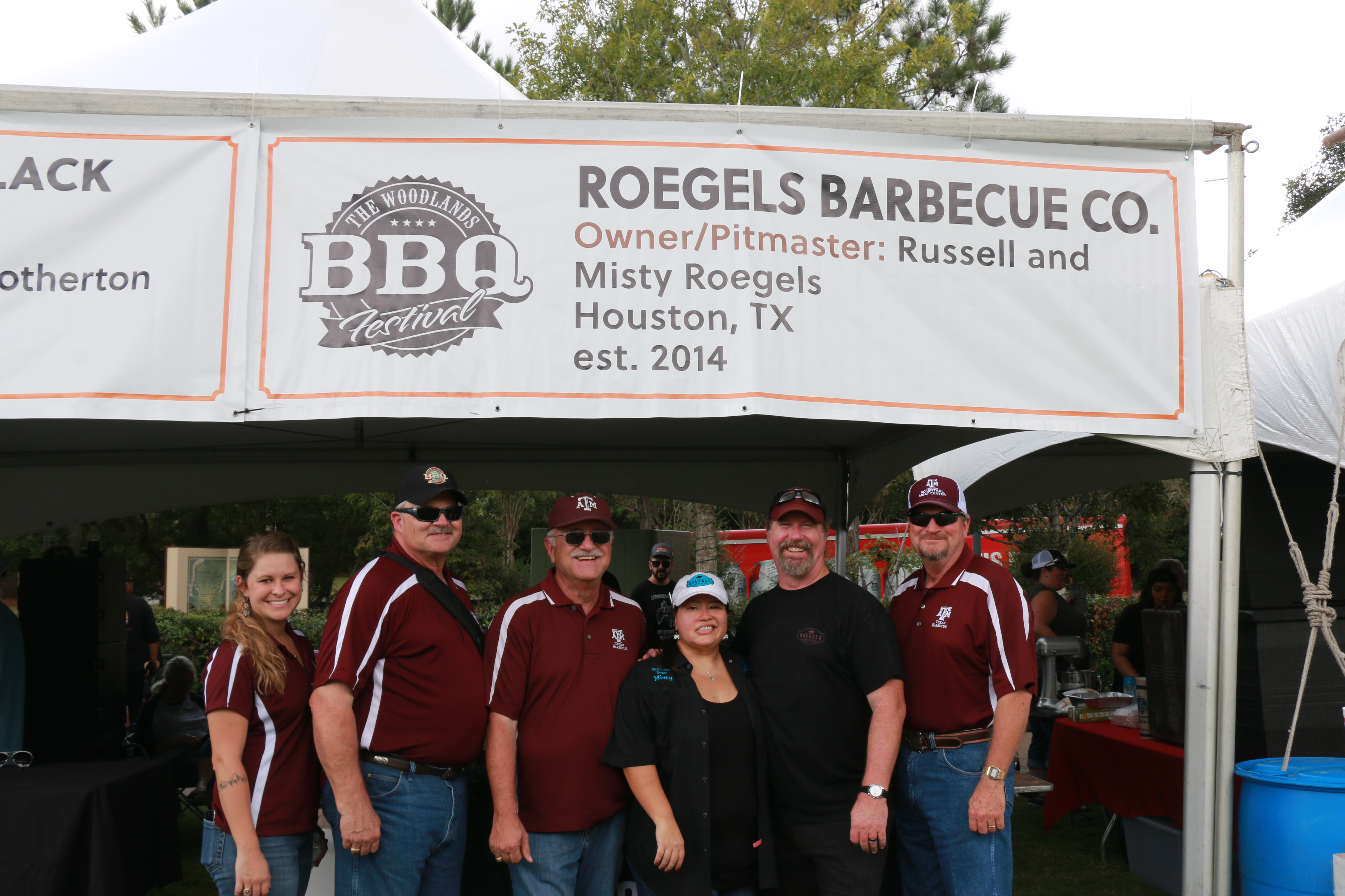 Brogan, Davey, Jeff, Misty Roegels, Russell Roegels, and Ray in front of the Roegels Barbecue booth at The Woodlands BBQ Festival