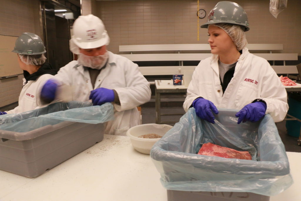 Trent Schwartz and Jenna Hunt seasoning briskets