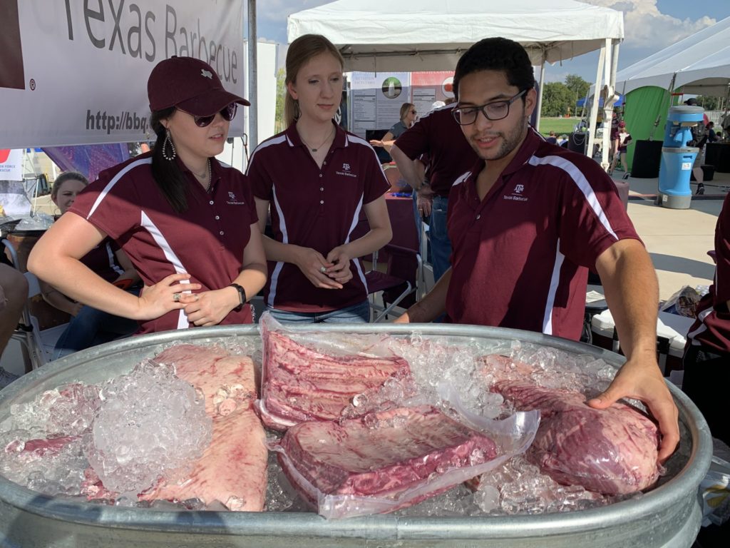 Haley Wilkins, Ashley Fuqua, and Luis Erazo and the cuts of beef used for barbecue at the RELLIS Festival