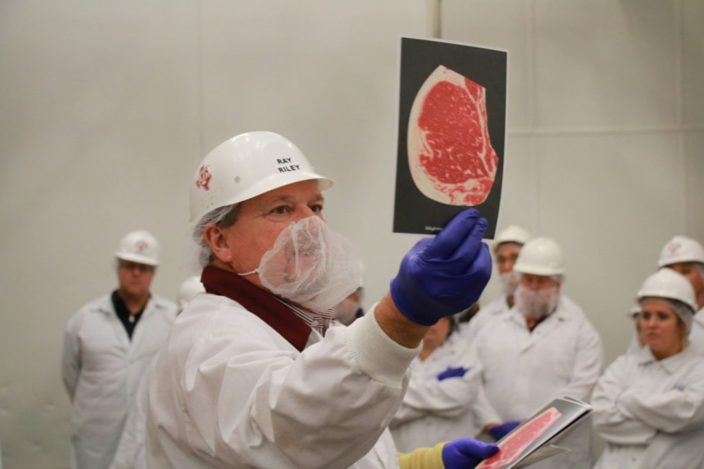 Ray Riley showing beef marbling levels at the Texas Barbecue Town Hall Meeting