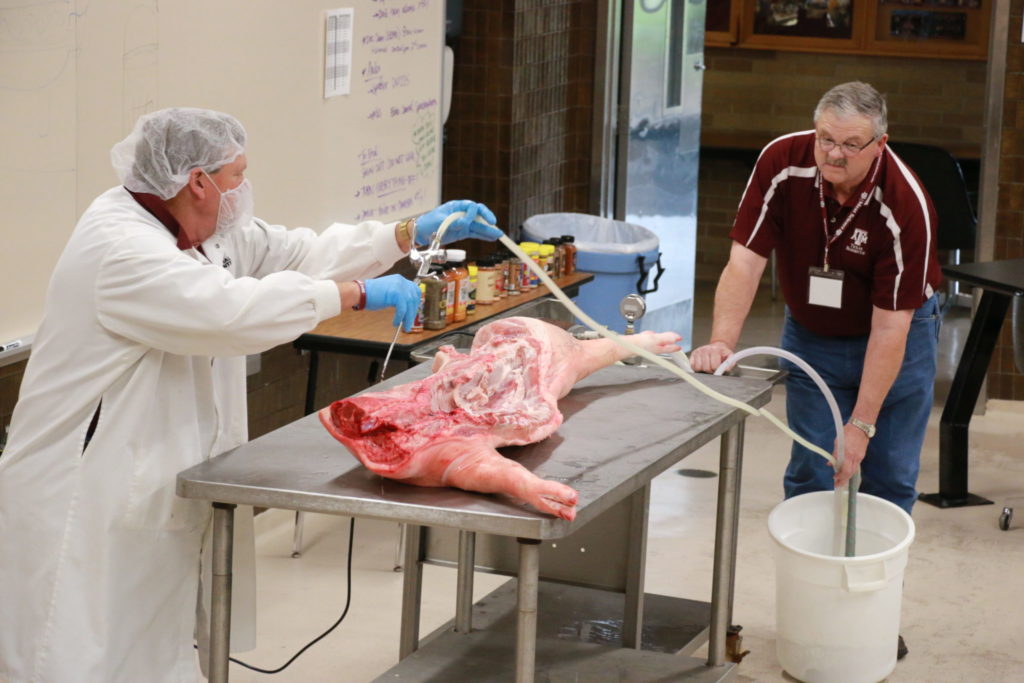 Ray Riley and Davey Griffin pumping brine in pork carcass side